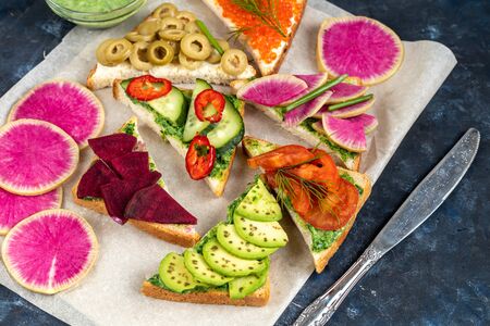 Holiday sandwiches of various shapes. Vegetarian and more. Dressing with avocado and spinach and creamy yogurt. Top cucumber, turnips, tomatoes, salami, balyk, red caviar, spinach, eggs and olives.の写真素材