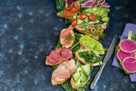 Holiday sandwiches of various shapes. Vegetarian and more. Dressing with avocado and spinach and creamy yogurt. Top cucumber, turnips, tomatoes, salami, balyk, red caviar, spinach, eggs and olives.の写真素材