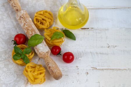 Ingredients for cooking Italian pasta. Pasta, basil, cheese, cherry tomatoes, olive oil, egg, yolk. On a light background. Copy space.の写真素材