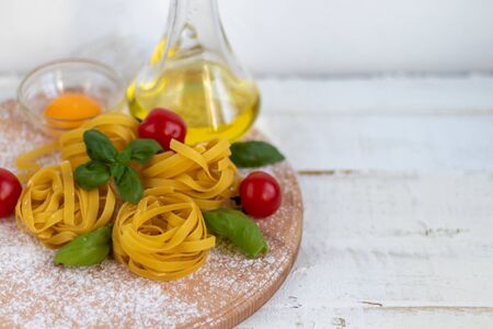 Ingredients for cooking Italian pasta. Pasta, basil, cheese, cherry tomatoes, olive oil, egg, yolk. On a light background. Copy space.の写真素材