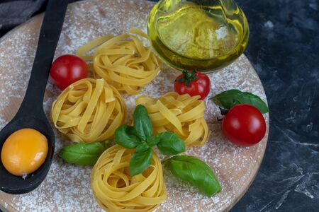 Ingredients for cooking Italian pasta. Pasta, basil, cheese, cherry tomatoes, olive oil, egg, yolk. On a light background. Copy space.の写真素材