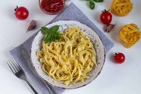 Italian pasta, spaghetti with avocado, spinach, basil, cream, cheese. Vegetarian vegetable pasta. Spinach with noodles. On a light background. Nearby are cherry tomatoes, olive oil. Copy space.の写真素材