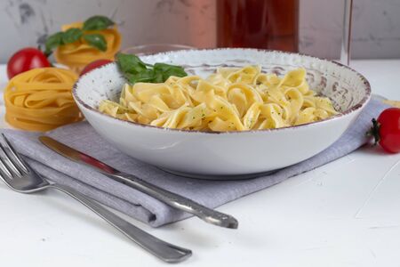 Italian pasta, spaghetti with avocado, spinach, basil, cream, cheese. Vegetarian vegetable pasta. Spinach with noodles. On a light background. Nearby are cherry tomatoes, olive oil. Copy space.の写真素材
