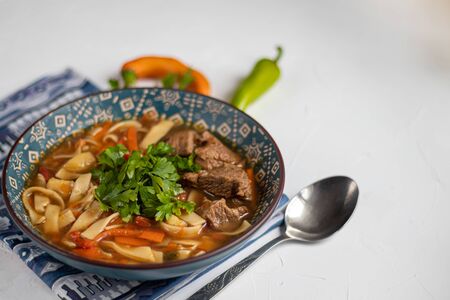 Eastern dish Lagman. Noodles, beef, blue, pepper, tomatoes. Hearty dish. Top decorated with parsley and cilantro. On a dark background. Copy space.の写真素材