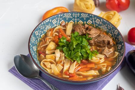 Eastern dish Lagman. Noodles, beef, blue, pepper, tomatoes. Hearty dish. Top decorated with parsley and cilantro. On a dark background. Copy space.の写真素材