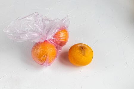 Environmentally harmful packages, spoiled fruits that lie in them. Ugly food. Copy space. Light background.の写真素材
