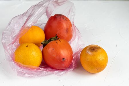 Environmentally harmful packages, spoiled fruits that lie in them. Ugly food. Copy space. Light background.の写真素材