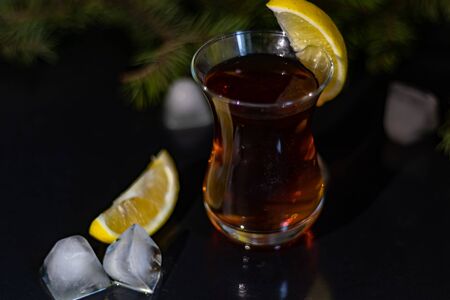 Turkish tea in a transparent glass with lemon slices. In the background is a Christmas tree branch. New Year. Black background. Copy space.の写真素材