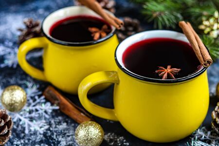 Christmas red wine mulled wine with spices and in large, yellow mugs. Around the white snow. New Year. Christmas decorations, cinnamon sticks. Copy space.の写真素材