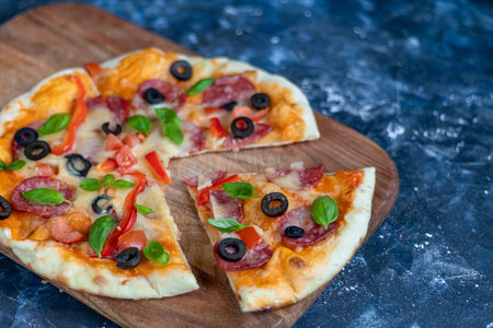 Delicious pizza with salami, sweet pepper, olives, mozzarella and basil. On a dark background. Copy...