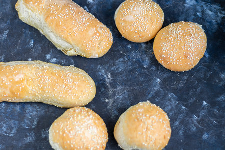 Buns cooked in the oven. Sprinkled with sesame seeds. Yeast dough. On a dark background. Copy space....