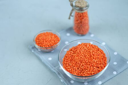 Red lentils in a plate and in a metal spoon on a background under concrete. Ideal food for vegetarians. Copy space.の写真素材