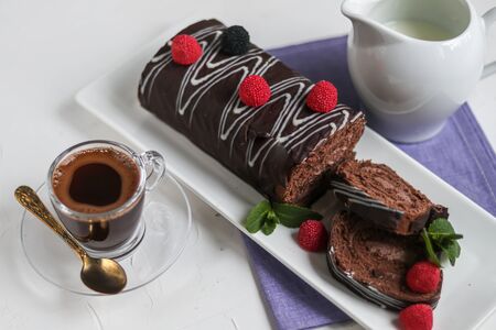 Sliced chocolate roll. Decorated with strawberries. Copy space. Christmas, New Year mood. Breakfast with a cup of coffee.の写真素材
