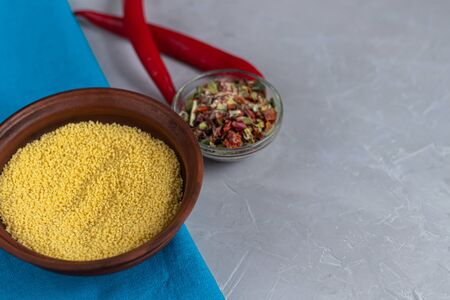 Raw couscous groats, a glass of clean, hot water and dry vegetables. Everything for cooking porridge with vegetables. Vegetarian food, healthy nutrition. Copy space.の写真素材