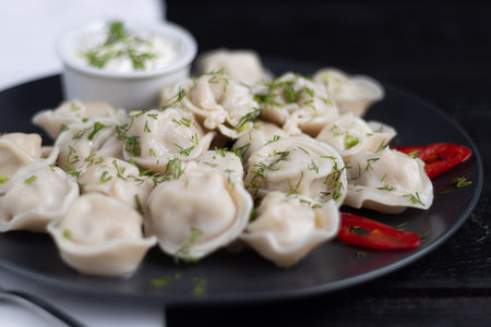 Boiled dumplings decorated with onions and peppers. In the background are greens, red peppers and...