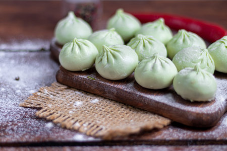 Frozen dough khinkali with spinach. Garnished with Red Chilli, Dill and Parsley. On a wooden...