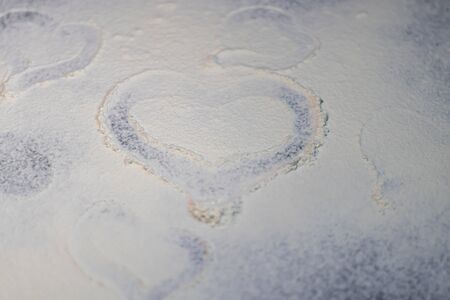 Flour is sprinkled on the table. They draw a heart on it with a finger. Valentine's Day. Dark marbled background. White flour.の写真素材