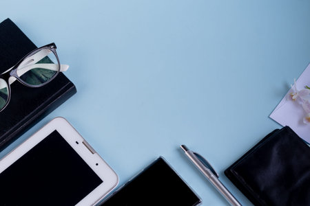 A light blue table with the necessary items on it. Diary with pen,  phone. White cup of coffee. Top...
