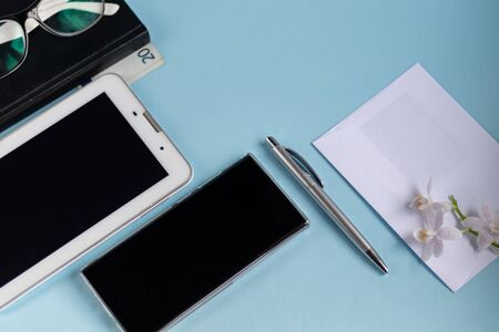 A light blue table with the necessary items on it. Diary with pen,  phone. White cup of coffee. Top view with copy space, flat lay.の写真素材