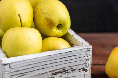 Golden apples are collected in a wooden, light, natural, environmentally friendly box. Harvesting. Delicacy for guests, vegetarian food, healthy food.の写真素材