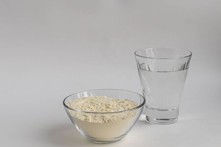 Collagen powder in a transparent bowl with a spoon for measuring quantity. Extra protein intake. Natural supplements for beauty and health. Collagen based plant concept. Flatlay, top view. Copy spaceの写真素材