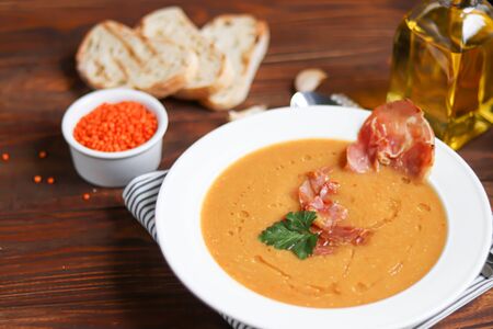 Vegetable soup with lentils on a wooden background. Served with chopped cherry tomatoes and herbs. Nearby are pieces of ciabatta. Raw groats in the background. Vegetarian dish. Copy spaceの写真素材