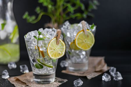 Refreshing summer alcoholic cocktail Margarita with crushed ice, lime and mint for decoration. Vodka splash. On a dark wooden background. On the leaves of the newspaper. Copy spaceの写真素材