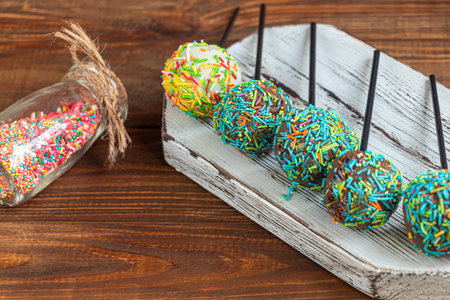 A colorful cake pops up, lying on a table. It is covered with sweet multi-colored sweets. Copy space