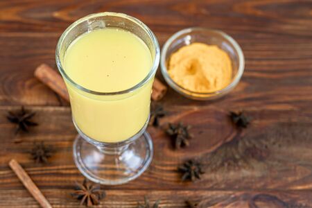 Masala tea or a traditional Indian drink with milk and spices, useful in winter to enhance immunity. On a wooden background. Copy spaceの写真素材