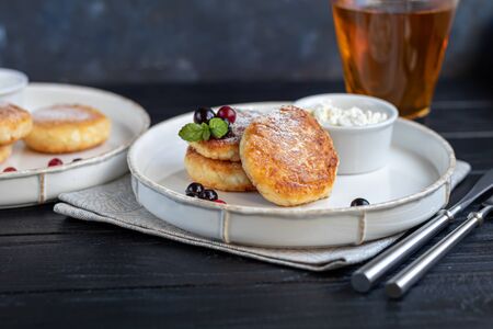 Homemade pancakes with cottage cheese on a dark lantern with black currants and cranberries. Breakfast for the whole family. Healthy vegan food concept. Copy space.の写真素材
