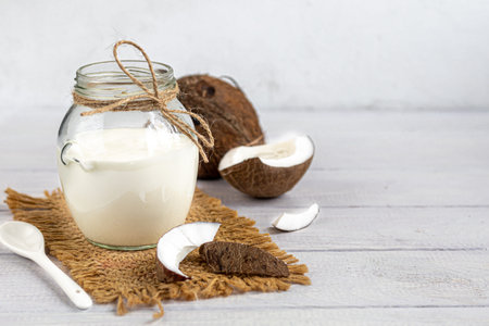 Homemade yogurt in a glass jar on a wooden light background with a ceramic spoon. Healthy diet food....