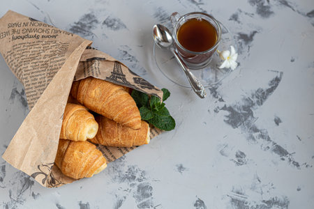 Croissants and coffee for breakfast with fresh raspberry jam on a light background. Decorated with a sprig of mint. Copy space.の写真素材
