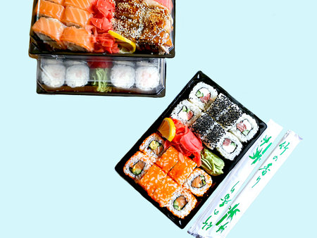 Home delivery food. Quarantine, safe food intake. Sushi boxes, salads with shrimp. Soy sauce.