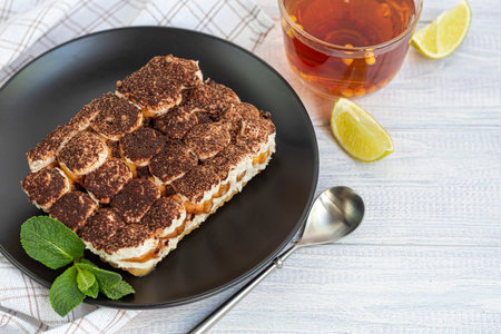 Tiramisu. Traditional italian dessert on a white background under concrete. Garnished with a sprig...