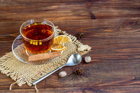 Sea buckthorn tea in a transparent cup. Vitamin drink. Increases immunity in case of viral infection. Near spices, tiramisu cake. Copy spaceの写真素材