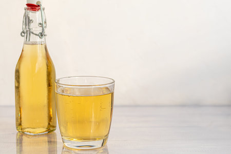 Healthy organic foods. Apple cider in a glass bowl and fresh red apples on a light background. In a glass of ice cubes and nearby cinnamon sticks. Copy spaceの写真素材