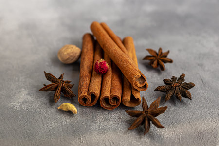 Cinnamon sticks, anise stars and nutmeg on a gray background. Near slices of chips from an orange....