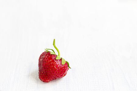 Large ripe strawberries are collected from the garden. On a white wooden background. Homemade winter fruit blanks. Selective focus. Copy spaceの写真素材