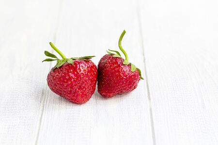 Large ripe strawberries are collected from the garden. On a white wooden background. Homemade winter fruit blanks. Selective focus. Copy spaceの写真素材