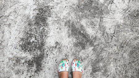 Cracked concrete floor, natural texture. Light table. Feet are on the floor. Abstraction.