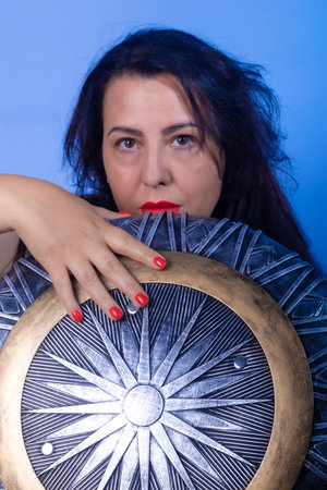 Portrait of a European woman with a shield and sword in her hands. Shooting in the studio. Close-up,...
