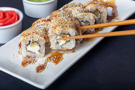 Sushi Sets Uramaki,  Philadelphia, on a white plate. Nearby ginger and wasabi. Soy sauce in a white bowl. On a dark background. Copy space.の写真素材