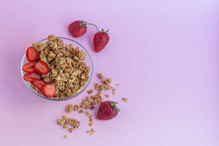 Homemade granola with strawberry slices on a pink background. Vegetarian dish. Healthy breakfast. Copy space.の写真素材