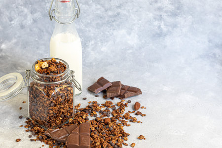 Homemade granola with strawberry pieces, chocolate and nuts in a glass jar. With the addition of...