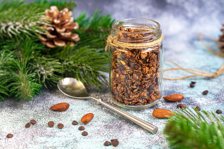 Homemade granola with chocolate and nuts in a glass jar. New year concept. On a gray background....