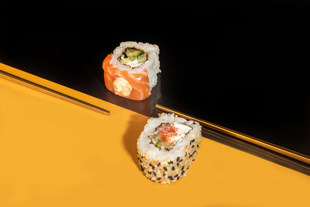 Sushi Sets Uramaki, California, Philadelphia, on a white plate. Festive, New Year concept. Against a dark reflective background. Copy spaceの写真素材