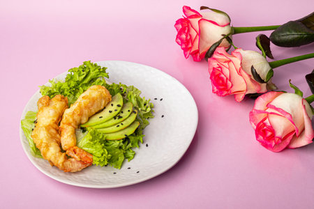 Avocado and king prawns salad on green leaves. Festive dinner. Healthy eating. On a pink background. Copy space.の写真素材