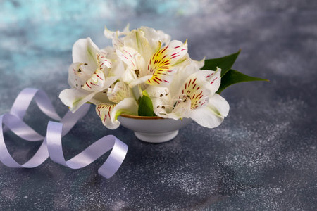 A bouquet of wild orchids on a light background decorated with ribbons. Mother's Day, Women's Day, Valentine's Day or Birthday. Baner. Copy space.の写真素材
