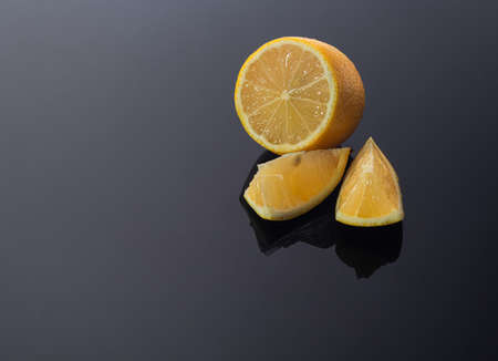 Lemon on a dark glossy background with a hard shadow. Vitamins and health concept. Copy space.の写真素材