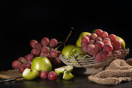 Bunches of pink grapes and green apples on a dark background. Still life. Vitamin basket. Copy...